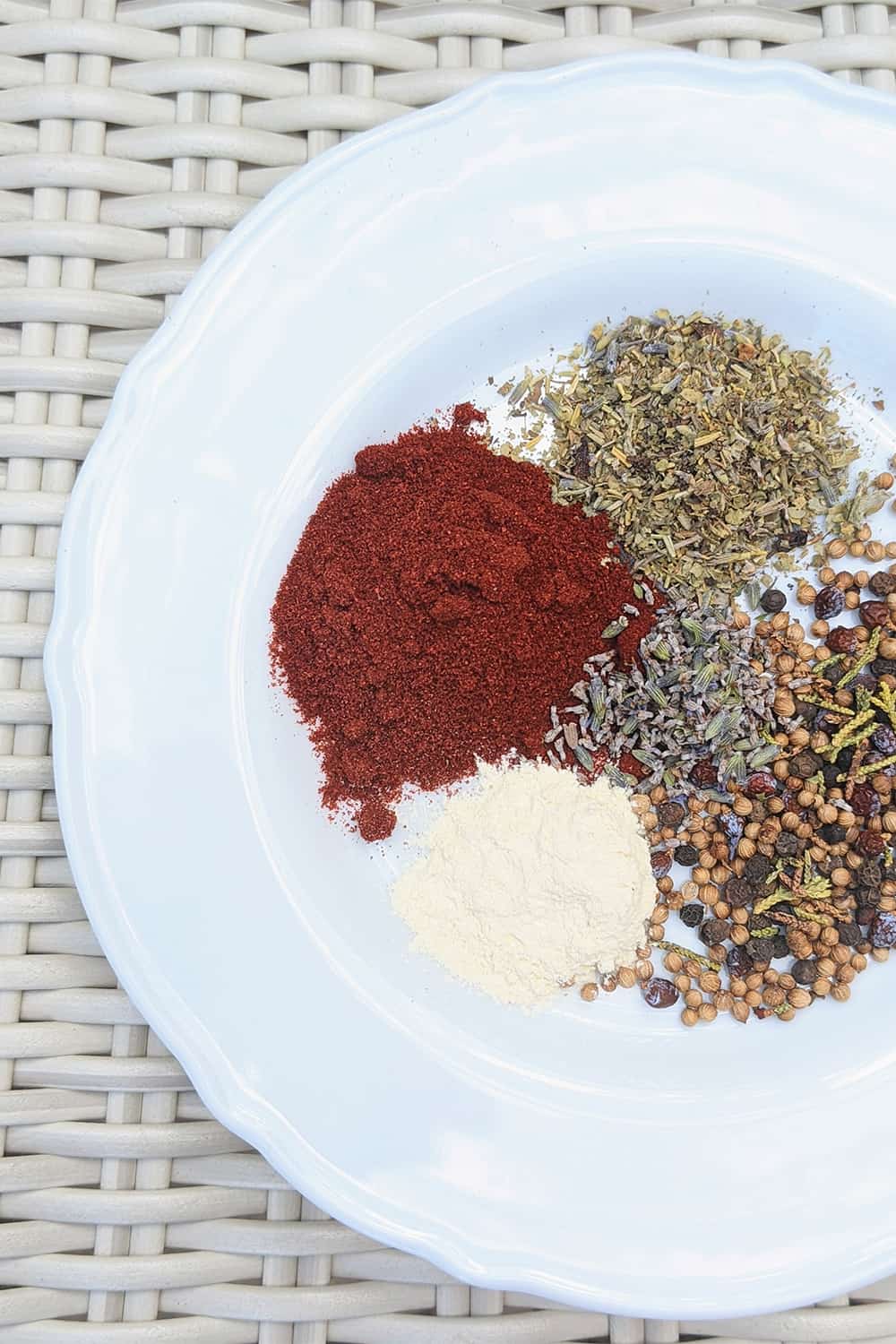 ingredients prepped on a plate including peppercorn, red chile powder, and more