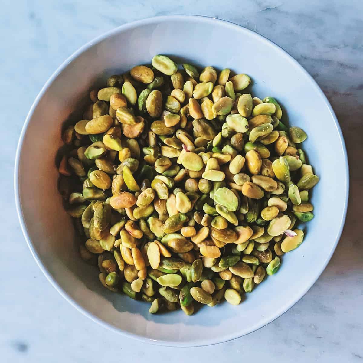 Pistachio Panna Cotta - pistachios peeled and resting in a white bowl